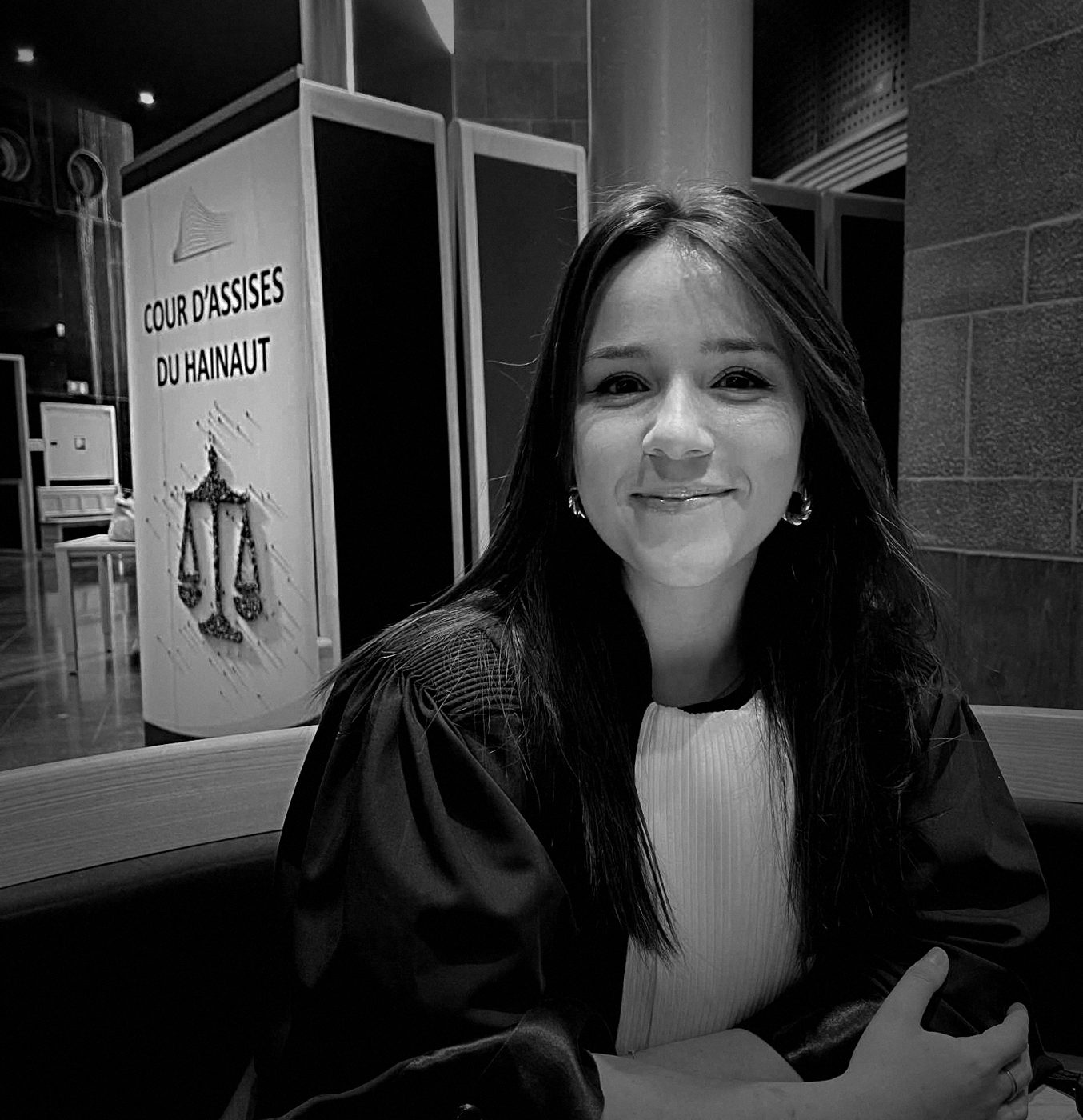 Laura Glorieux en robe d'avocate au palais de justice, devant le panneau de la Cour d'assises du Hainaut